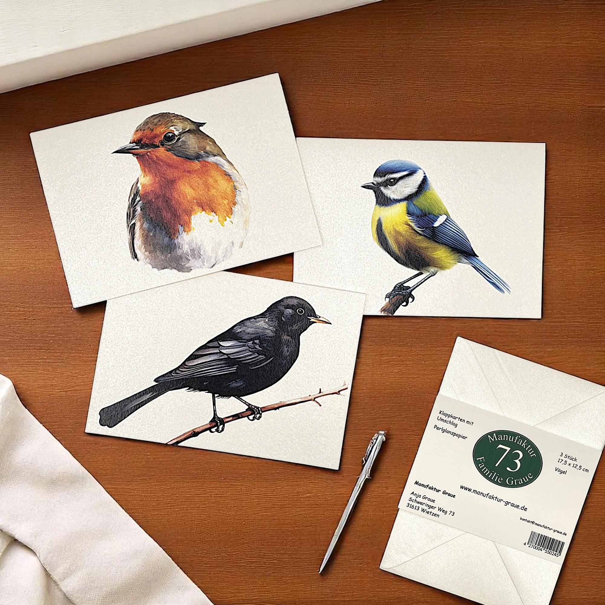 ein Kartenset mit Rotkehlchen, Blaumeise und Amsel liegen auf einem Tisch.
