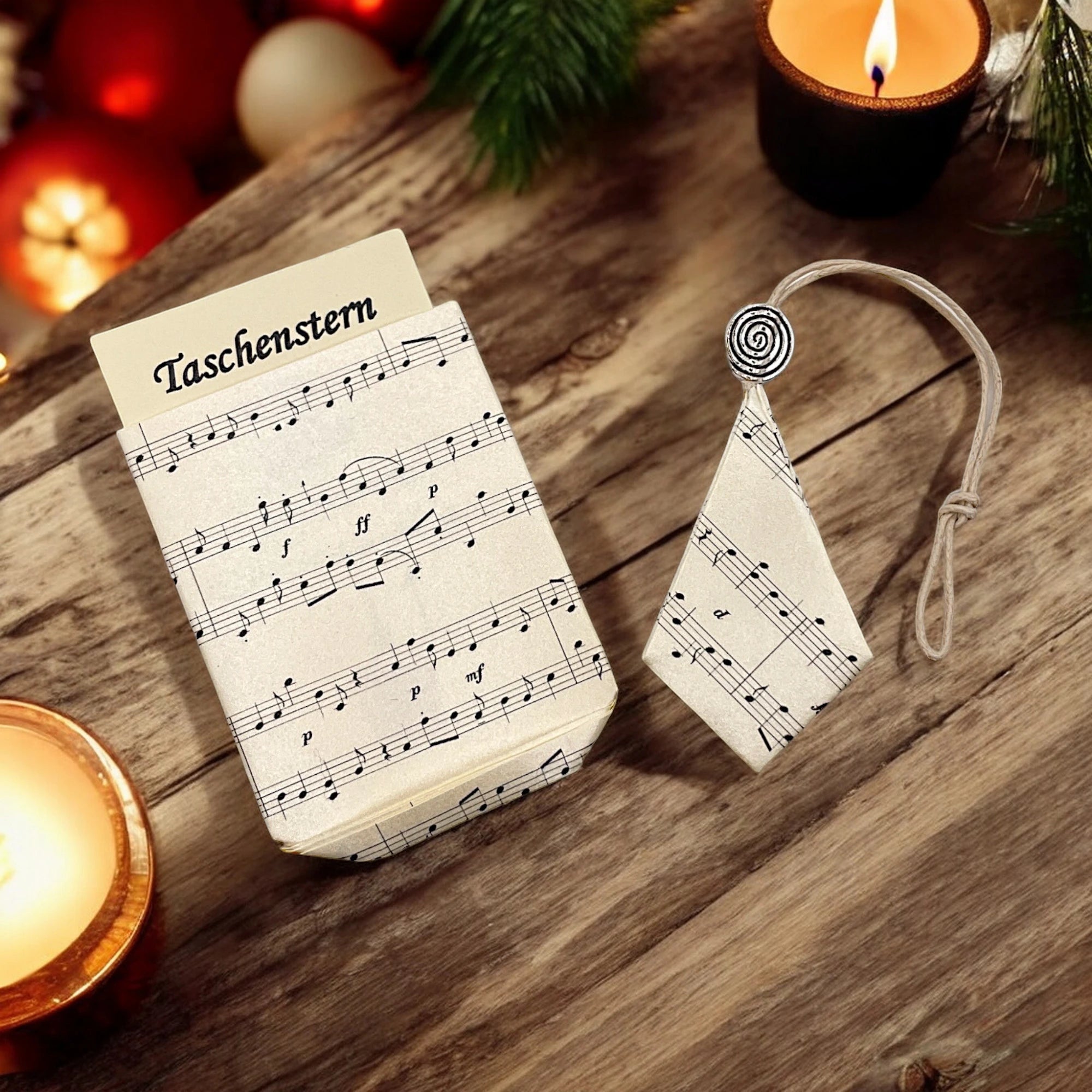 Faltstern-Papierstern mit Kerzen auf einem Holztischg mit grünen Zweigen