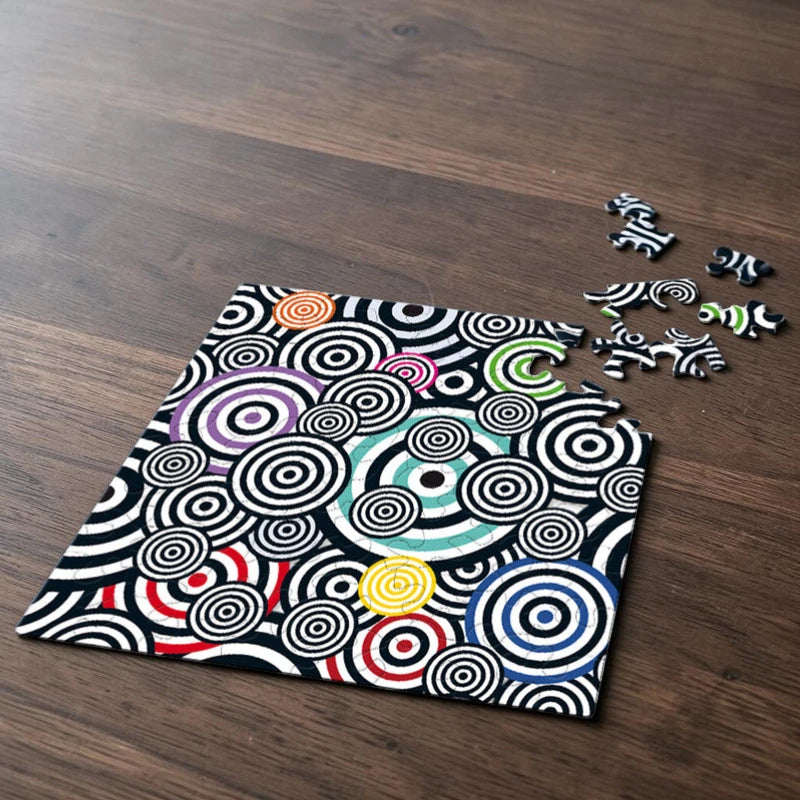 Puzzlebox und Puzzleteile des Curiosi-Puzzles „Bunte Kringel“, Q Pop 1 mit farbenfrohem Pop-Art-Motiv.