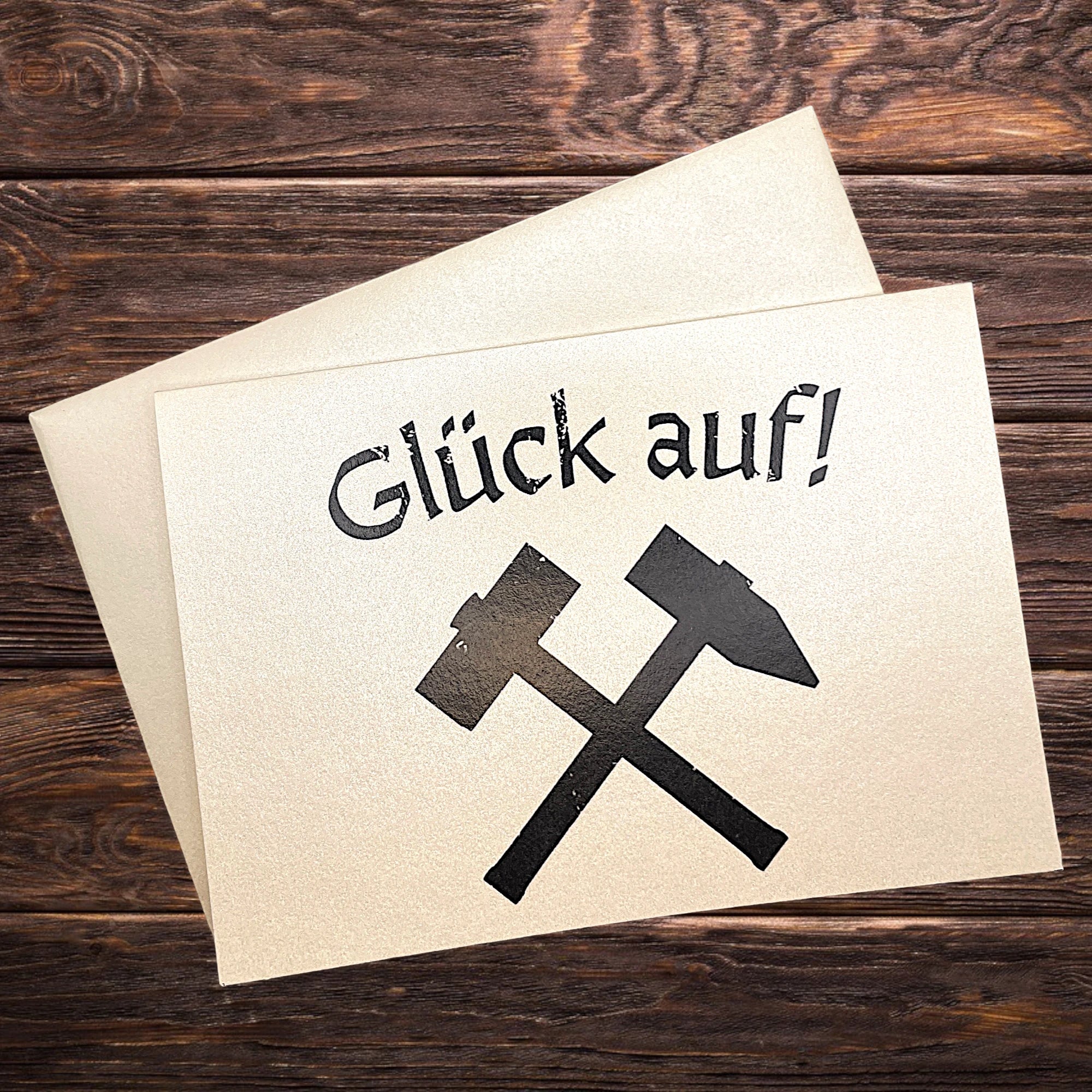 Traditionelle Klappkarte mit Bergbau-Symbol „Glück auf“, präsentiert auf rustikalem Holztisch