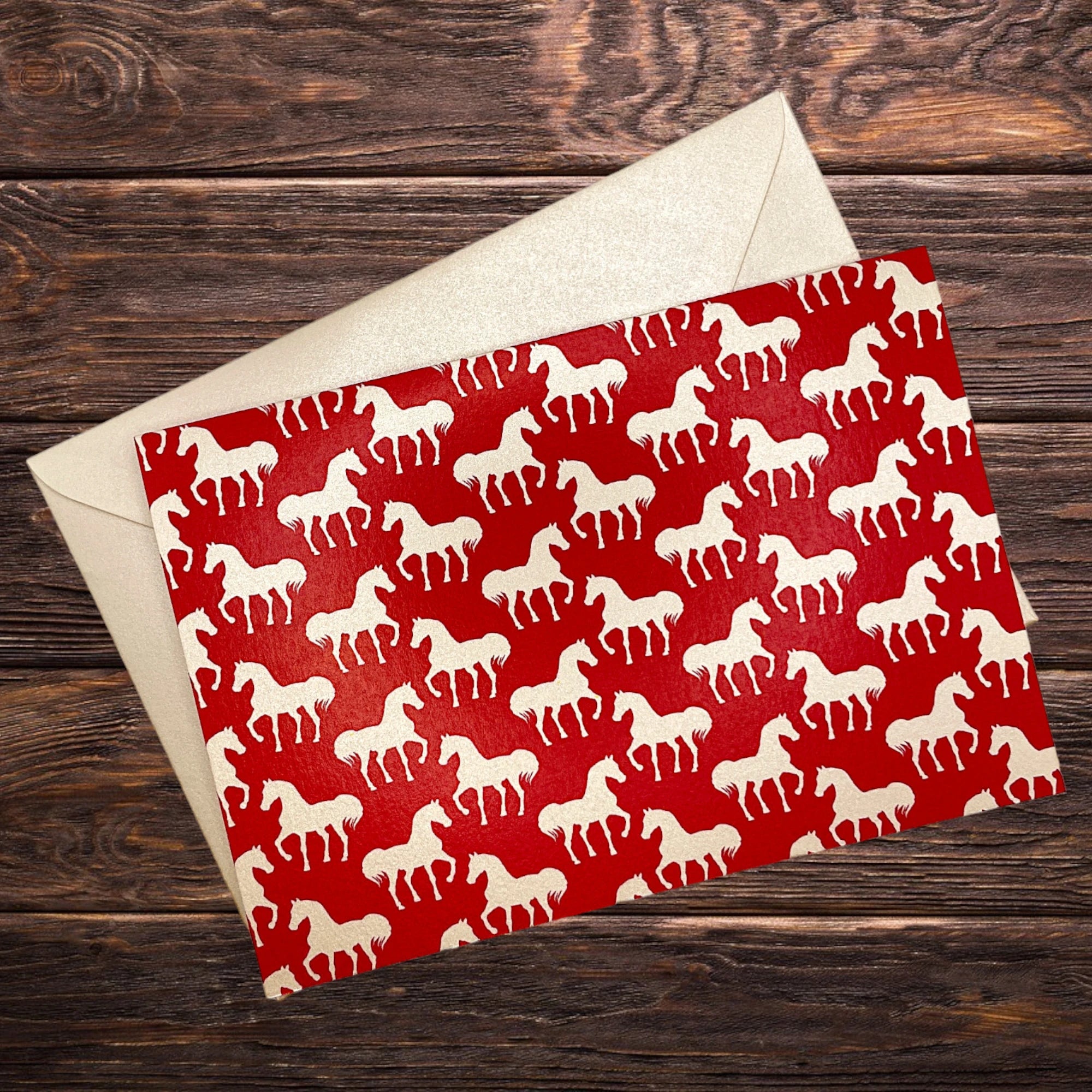 Elegante Klappkarte mit weißen Pferden auf rotem Hintergrund, dekorativ präsentiert auf rustikalem Holztisch