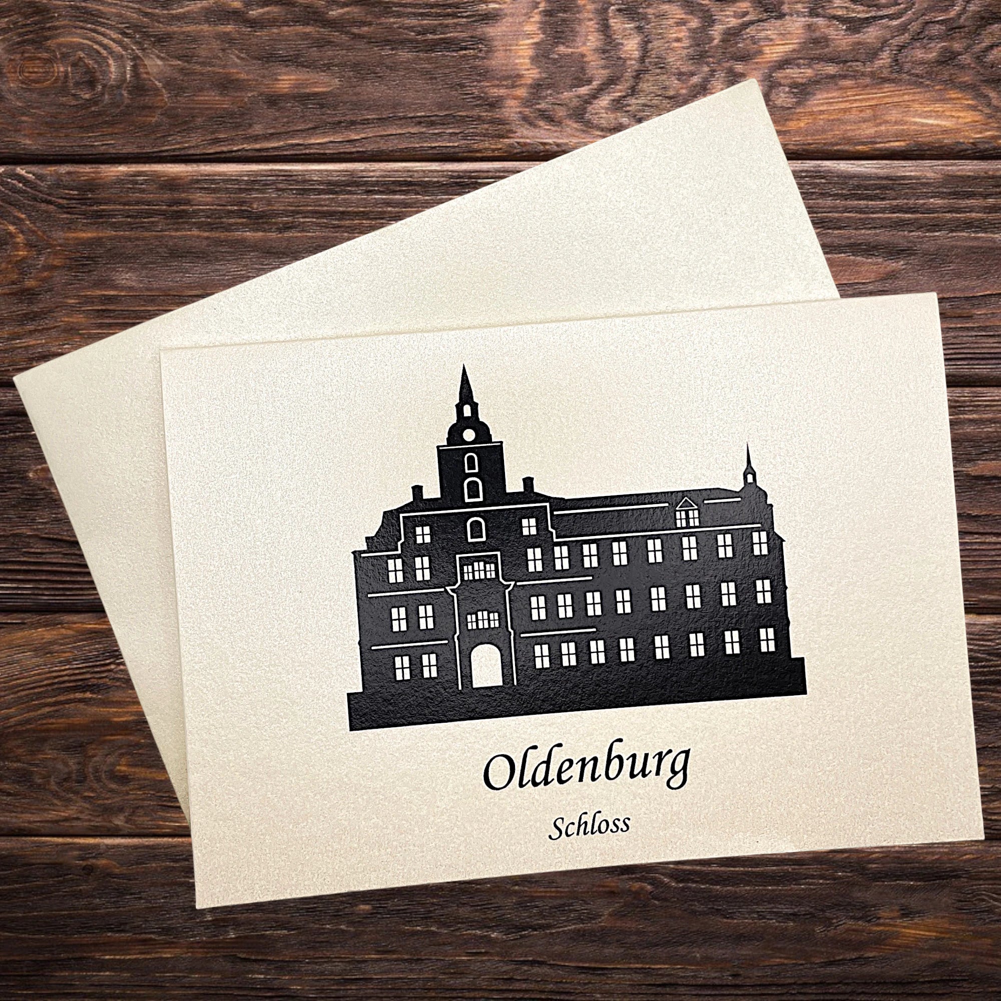 Klappkarte mit dem Oldenburger Rathaus in Schwarz – elegant inszeniert auf dunklen, rustikaler Tisch