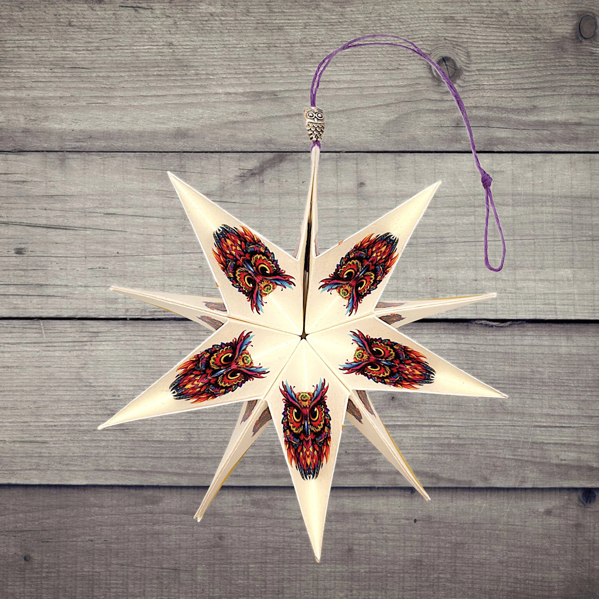 Papierstern mit bunter Eule, dekorativ präsentiert auf rustikalem Holzhintergrund