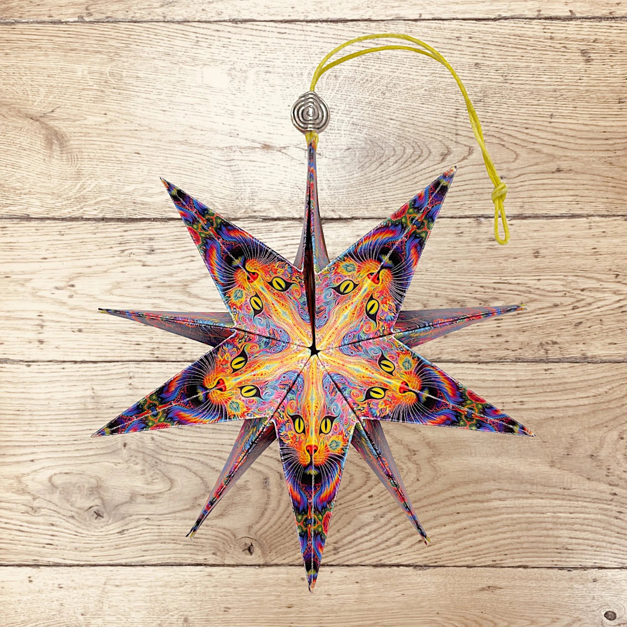 Dekorativer Papierstern mit lebhaftem Katzenmotiv auf rustikalem Holztisch