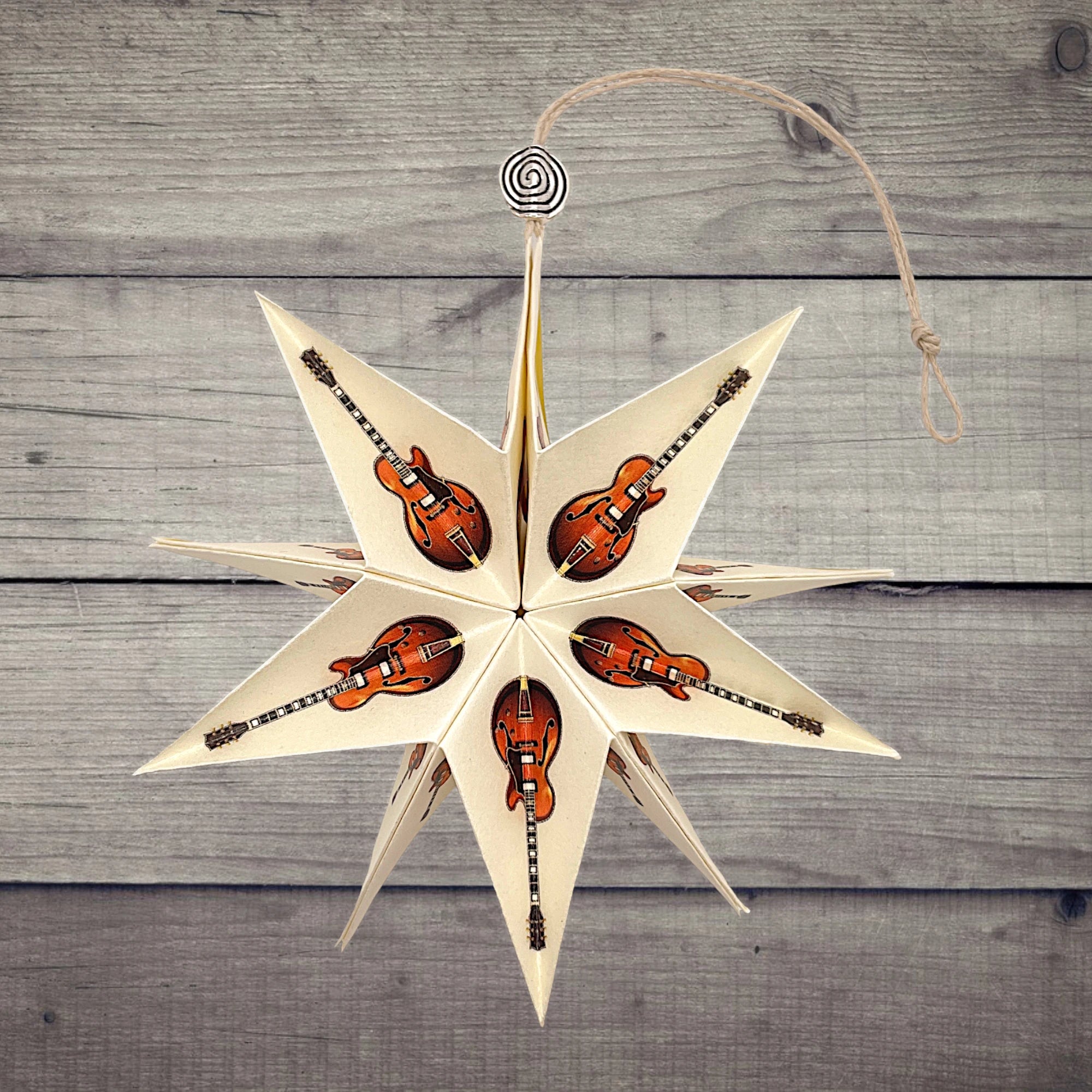Papierstern mit brauner E-Gitarre, dekorativ auf einem rustikalen Holztisch präsentiert