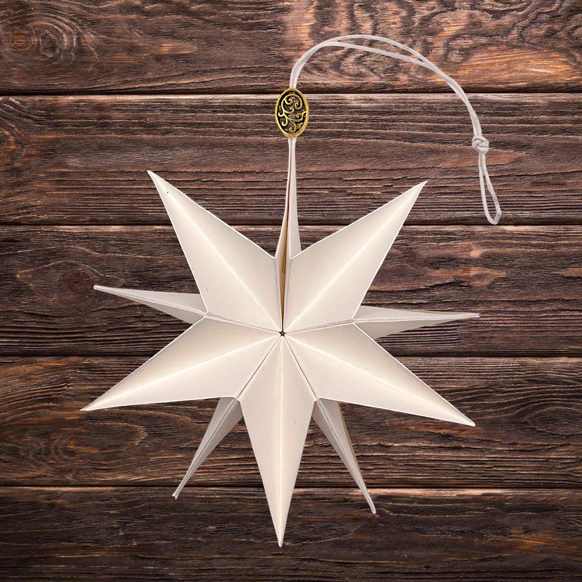 Dekorativer Papierstern in Gold-Weiß, festlich inszeniert auf rustikalem Holztisch
