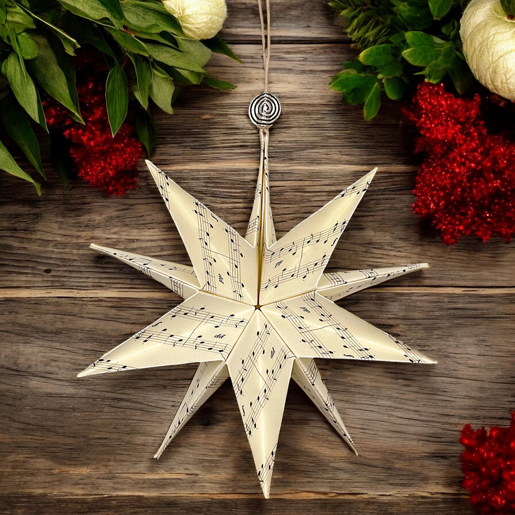 Papierstern mit musikalischem Motiv, vor dunklem Holz mit winterlicher Deko aus Beeren und Zweigen