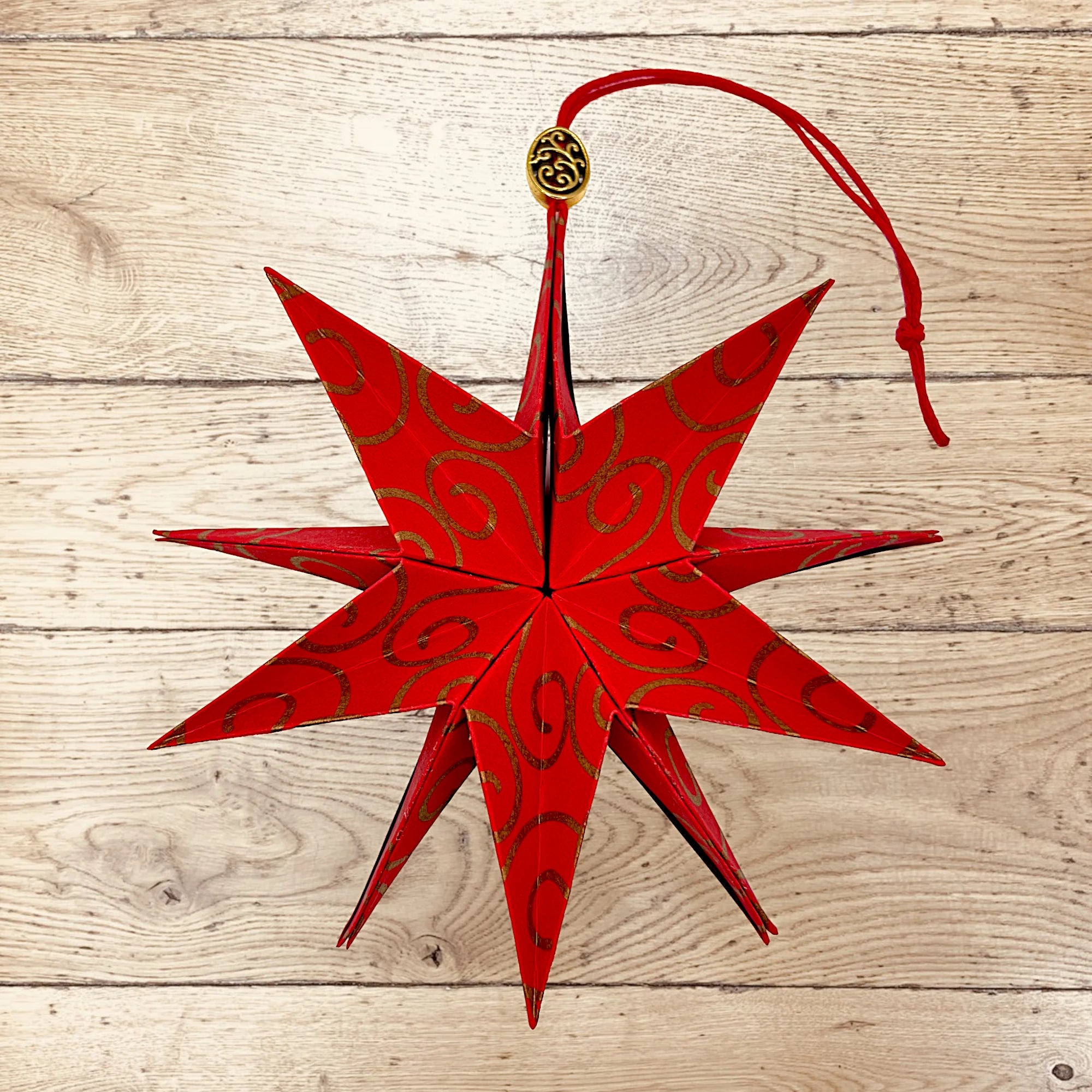 Papierstern mit goldener Arabeske, feierlich arrangiert auf Holztisch