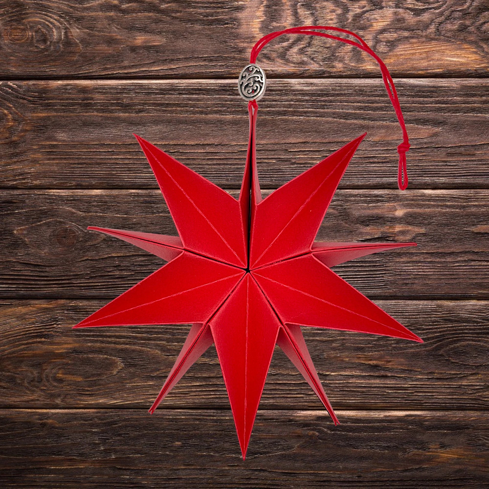 Glänzender Papierstern in festlichem Rot, dekorativ arrangiert auf rustikalem Holztisch