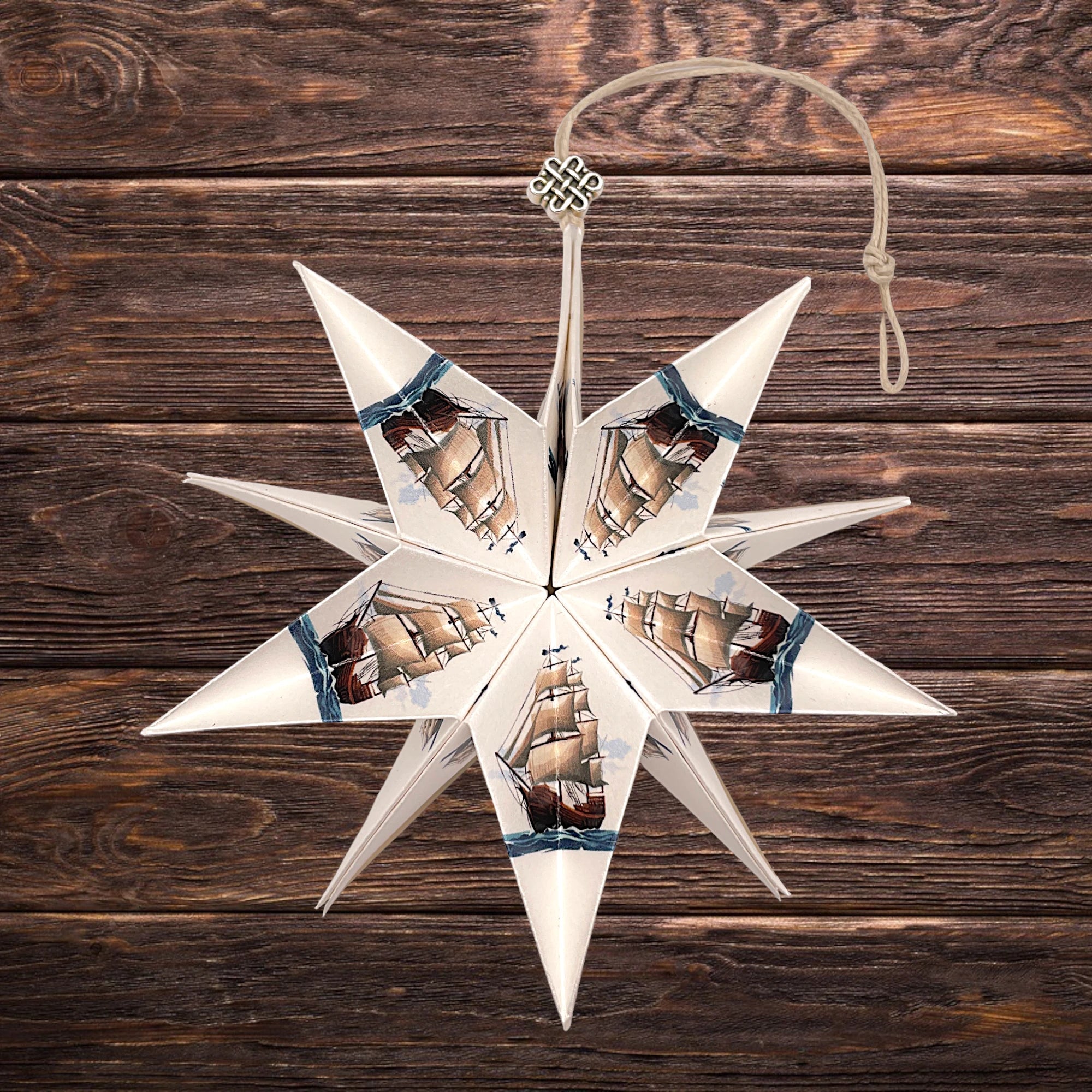 Dekorativer Papierstern mit Segelboot-Motiv, stilvoll präsentiert auf Holztisch
