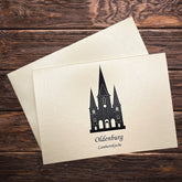 Auf einem Holztisch eine Karte mit Umschlag. Motiv die Lambertikirche aus Oldenburg