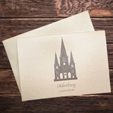 Auf einem Holztisch eine Klappkarte mit der Lambertikirche in grau