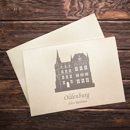 Auf einem Holztisch eine Klappkarte aus Oldenburg mit dem Alten Rathaus