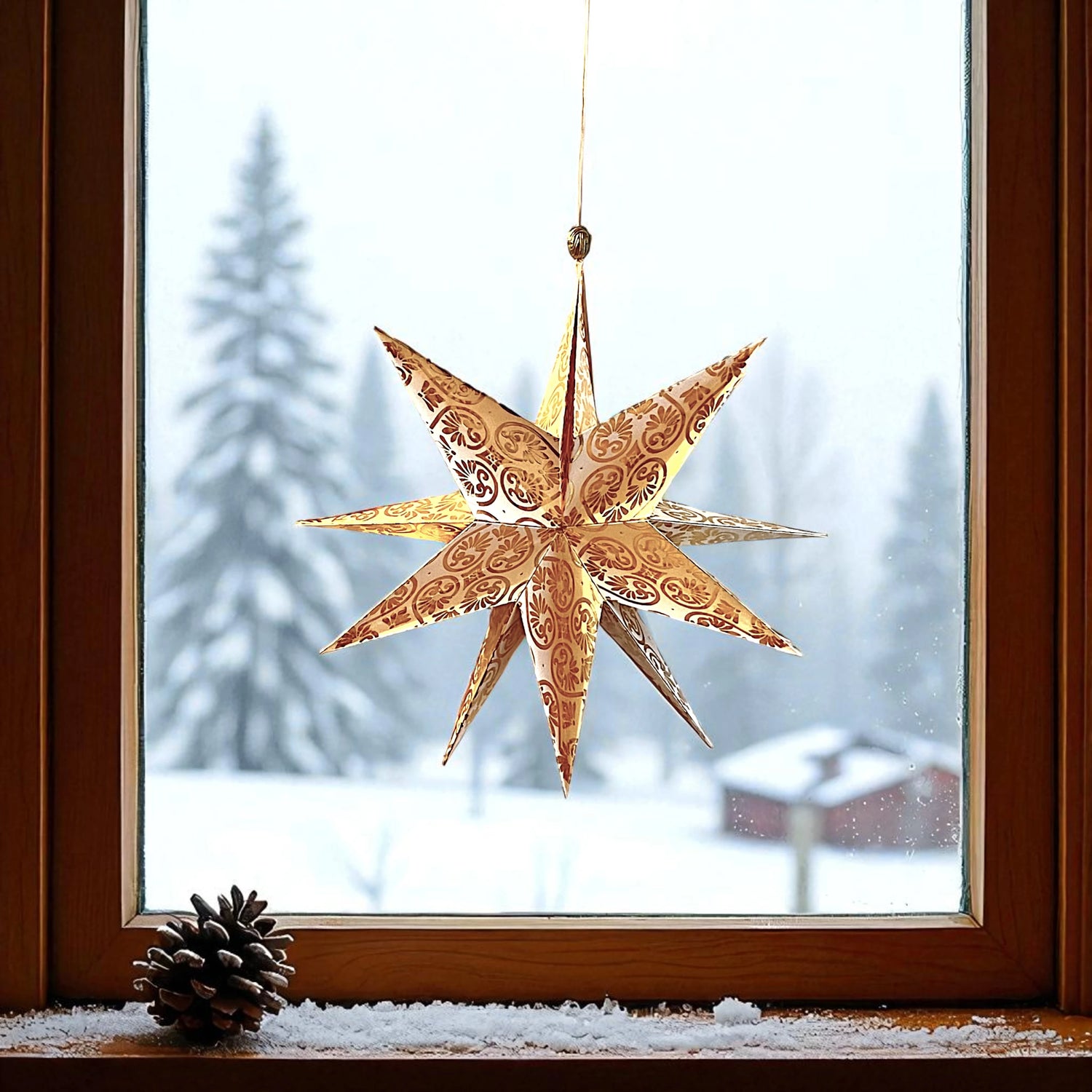 Taschenstern als Papierstern hängt in einem Fenster in gold