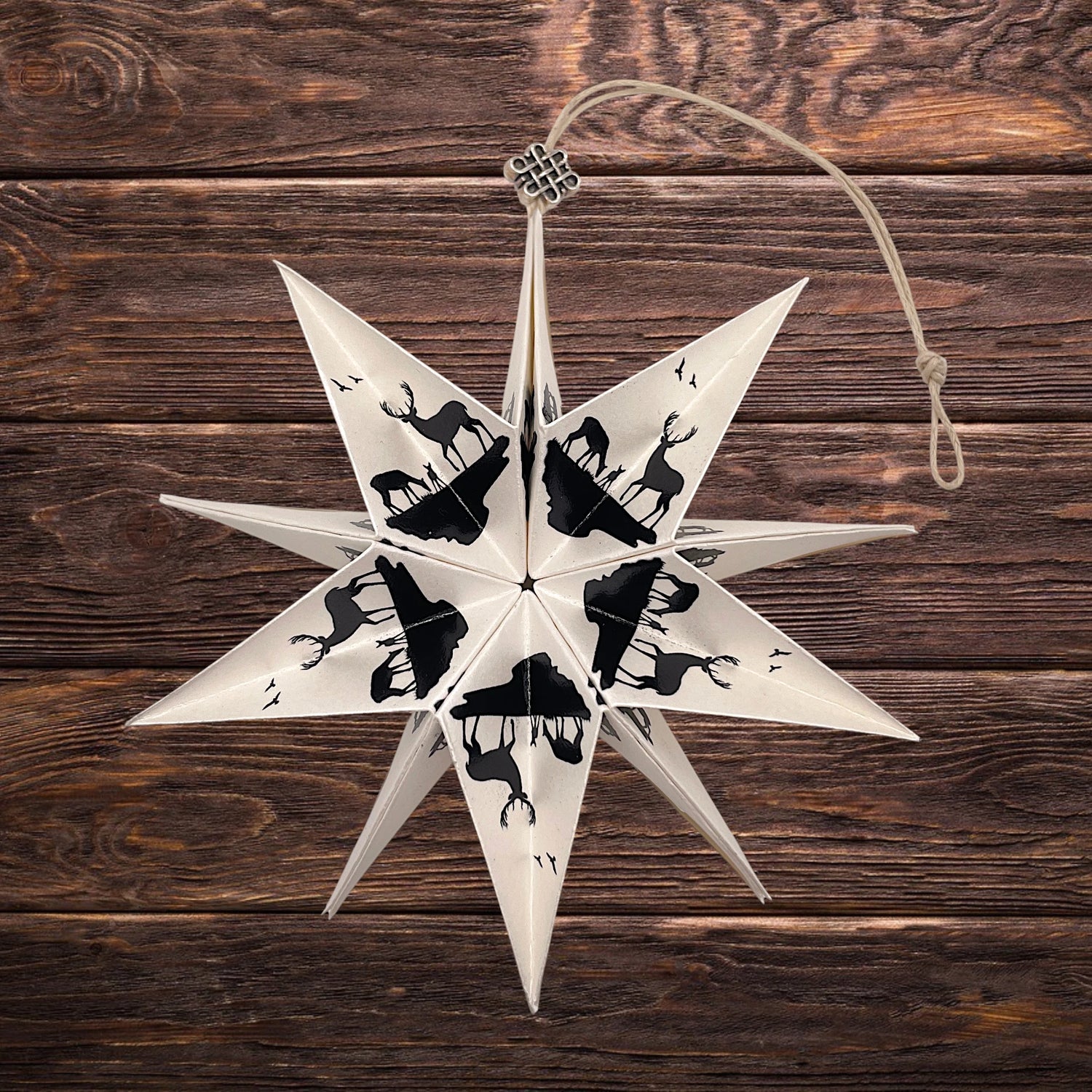 Handgefertigter Papierstern mit Schwibbogen aus dem Erzgebirge vor Holzwand – dekorativer Stern für Weihnachten und festliche Fensterdekoration.