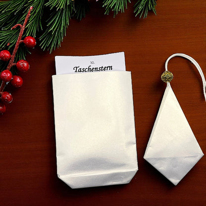 Liegend auf einem Tisch in einem Etui ein Papierstern in weiss mit gold