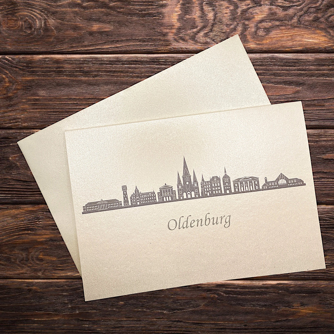 Klappkarte mit dem Druck in grau der Skyline Oldenburg auf einem Holztisch
