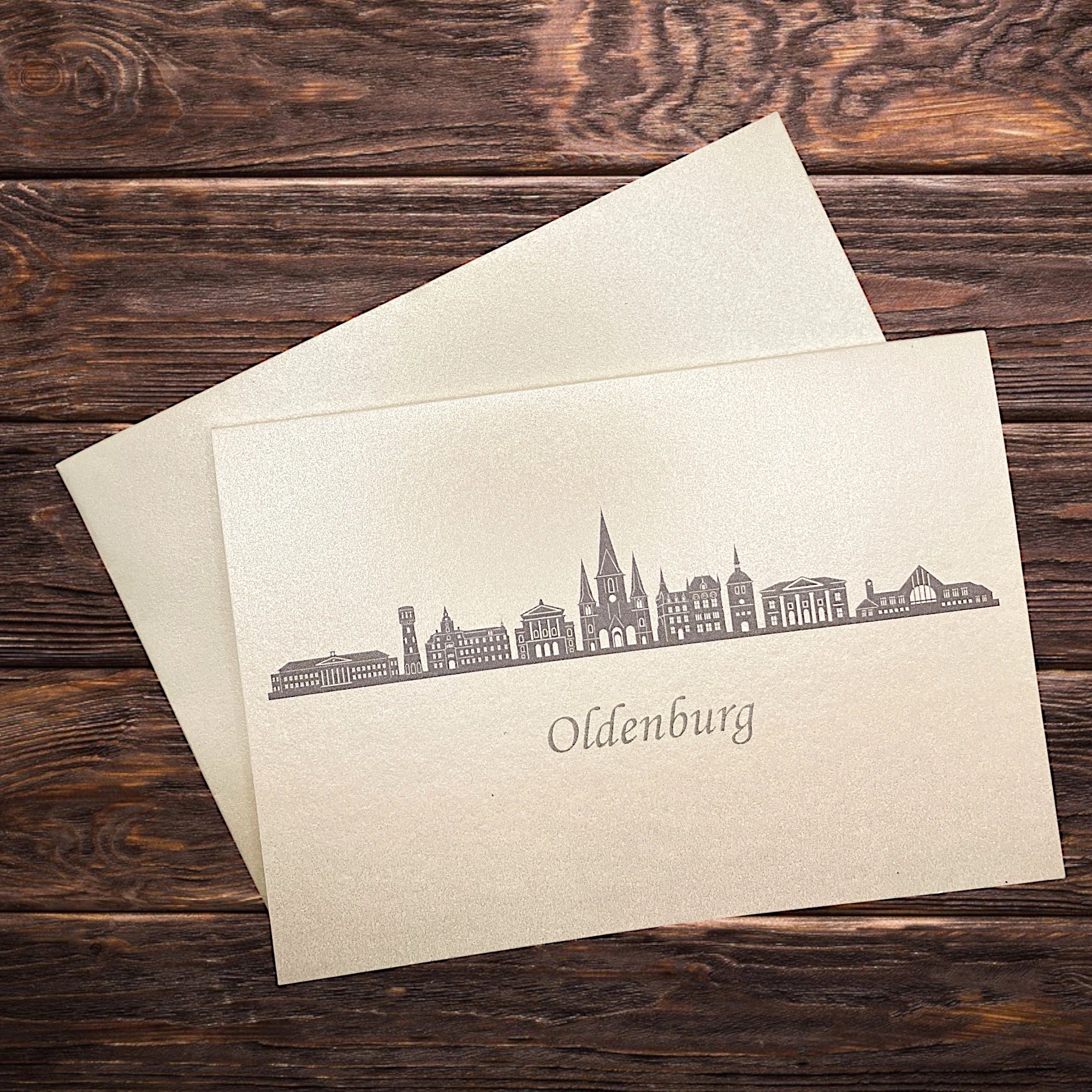 Klappkarte mit dem Druck in grau der Skyline Oldenburg auf einem Holztisch