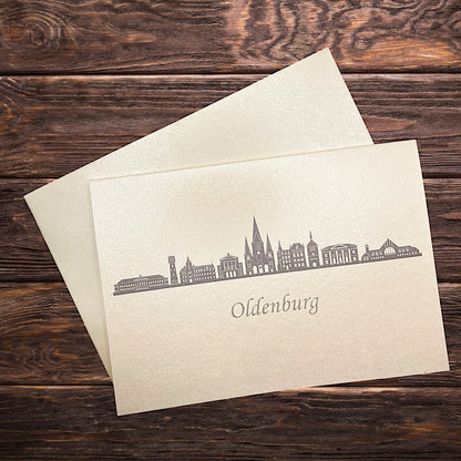Klappkarte mit dem Druck in grau der Skyline Oldenburg auf einem Holztisch