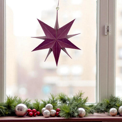 Hängender papierstern vor einem Fenster zu Weihnachten