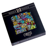 Puzzlekarton des Curiosi-Puzzles „Kunterbunte Stadt“ mit farbenfrohem Stadtmotiv.