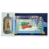 Weihnachtskarte als 3D Pop-up mit rotem Auto und Tannenbaum in verschneiter Landschaft.